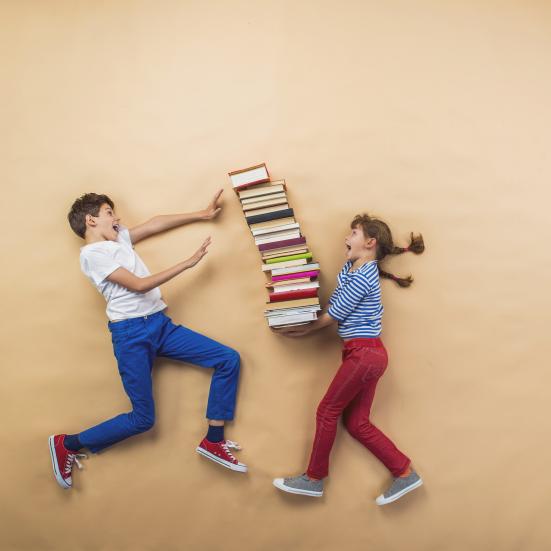 Billedet forestiller en dreng og en pige. Pigen har en stor stak bøger i hænderne.