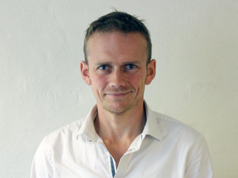 Billedet viser en smilende Jacob Tybjerg iført en hvid skjorte